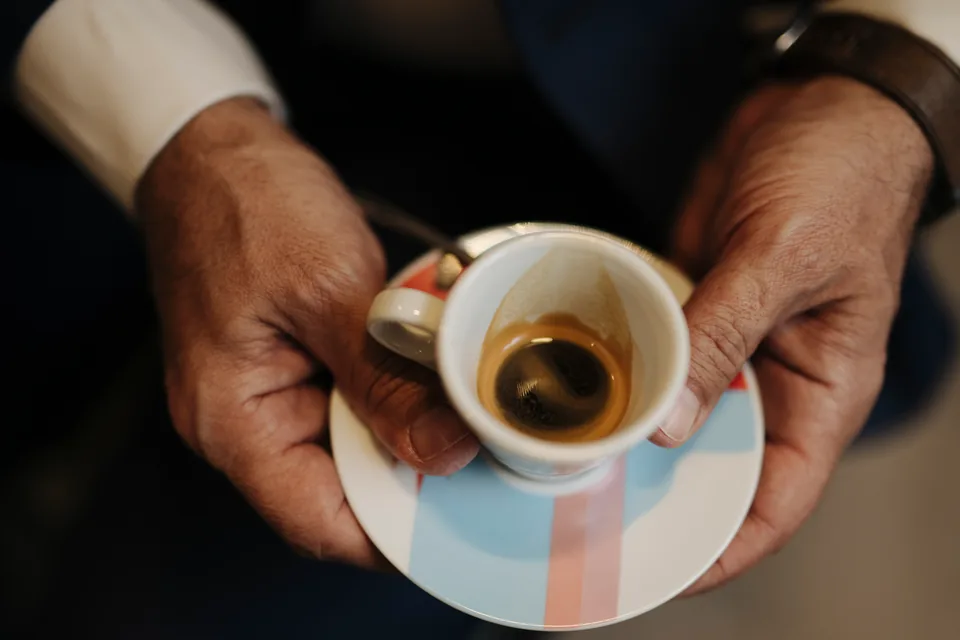 Montecristo No 4 Review — weathered hands holding a small cup of espresso on a saucer in warm light