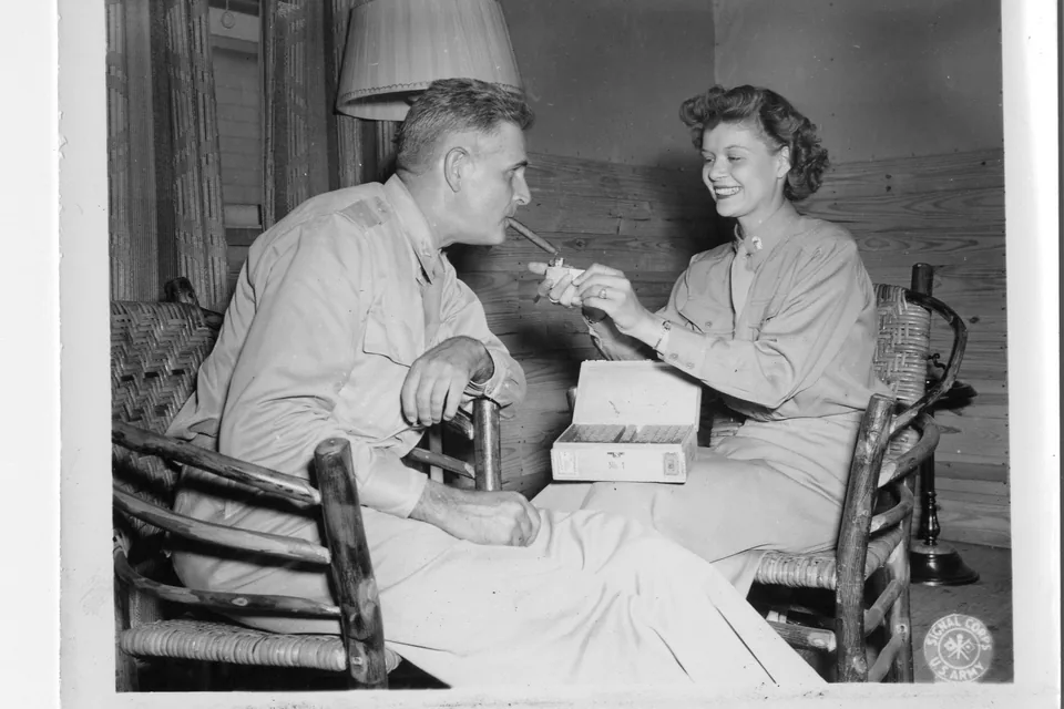 How to Light a Cigar — historic 1943 photograph of a woman lighting a cigar for a seated officer