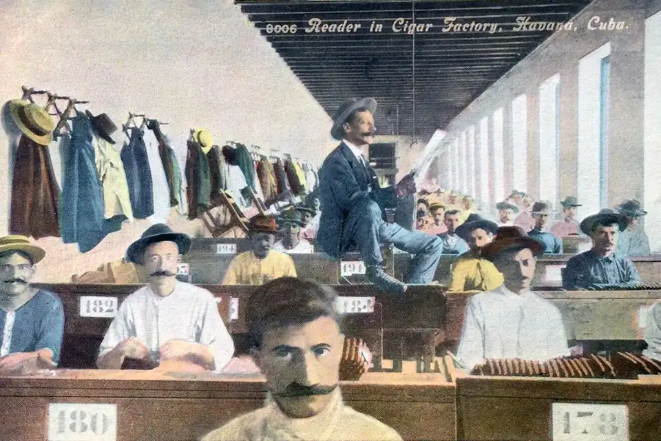 Early twentieth century postcard of a lector reading to cigar rollers in a Havana factory
